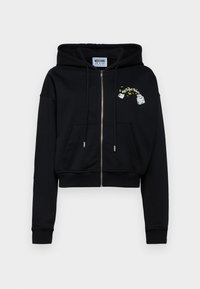 Črna krajšana zip-up kapuca, izdelana iz mehke tkanine. Ima sprednji žep, vrvici ter izvezen detajl z grafičnim dizajnom.