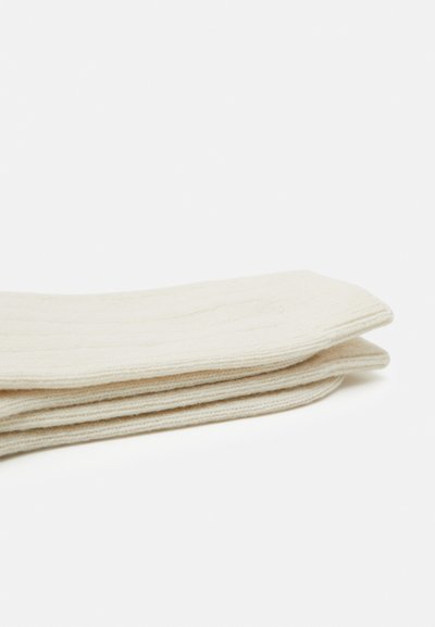 Beige strikkede sokker med ribbet tekstur, foldet pænt, lavet af et blødt materiale med en glat overflade.