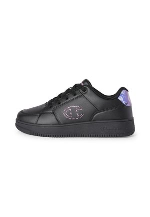 Czarny niski sneaker z różowym kropkowanym logo po boku i fioletowym wzorzystym elementem na pięcie, czarne sznurówki i fakturowana podeszwa.