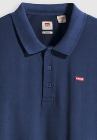Marineblauwe polo-shirt met een gestructureerde afwerking, drie knopen en een klein rood Levi's-logo op de linkerborst.