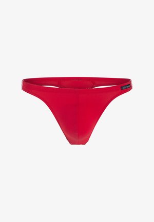 Ropa interior tipo tanga roja hecha de material liso y elástico. Cuenta con una pretina de tiro bajo y cobertura mínima en la parte trasera. Etiqueta de la marca visible.