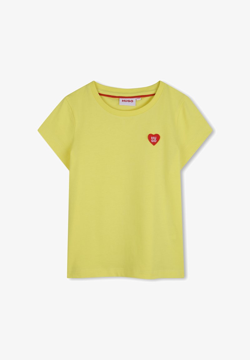 T-shirt jaune à manches courtes avec col rond et petit emblème en forme de cœur rouge sur la poitrine gauche affichant le texte blanc "HUGO".