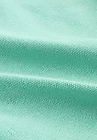 Textilie v světle modro-zelené barvě se hladkým povrchem a jemným diagonálním tkaným vzorem, předvádějící záhyby a drapériový efekt.