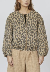 Leopardprint bomberjakke med quiltet tekstur, ribbet kant og lynlås foran. Puffede ærmer og en beige baggrundsfarve.