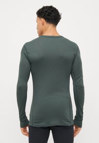 Langærmet, grøn skjorte i en tætsiddende design, lavet af et glat, struktureret stof med ribbede detaljer langs sømmene og manchetterne.