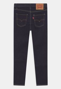 Mörkblå denimjeans med smal passform, med gyllene sömmar, en läderlapp på midjan och två bakfickor med emblematiskt mönster.