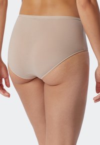 Mutande beige a vita alta con una sottile texture a righe, bordi lisci e una finitura morbida. Progettate per comfort e copertura.