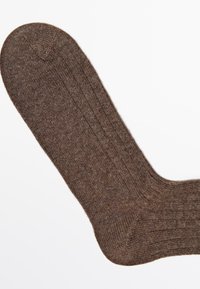 Brune ribbede sokker med rund tå og et tekstureret strikket design. Materialet virker blødt og er velegnet til hverdagsslub.