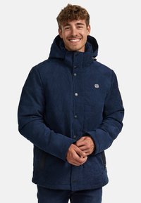 Marineblaue isolierte Jacke mit Kapuze, aus einem strukturierten Stoff, mit vorderen Druckknöpfen und seitlichen Taschen mit schwarzen Akzenten.