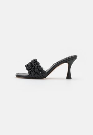 Mules à talons noirs avec une bride rembourrée décorée d'accents floraux texturés et un bout rectangulaire lisse. Dispose d'un talon effilé.