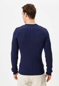 Granatowy sweter z prążkowanego dzianiny z długimi rękawami i okrągłym dekoltem, z teksturowanym wzorem i dopasowanym krojem.