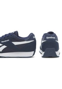 Granatowe trampki z białymi akcentami. Wykonane z zamszu i siateczki. Zapięcie na sznurówki. Posiadają logo Reebok na pięcie i boku. Teksturowana podeszwa.