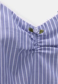 Haut en tissu rayé bleu et blanc avec un col festonné, orné d'un bouton décoratif en forme de fleur et de légères fronces au niveau de la poitrine.