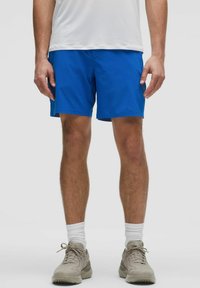 Blaue Sportshorts aus leichtem Material, mit elastischem Bund und einer Länge bis zur Mitte des Oberschenkels. Kombiniert mit grauen Schuhen und weißen Socken.