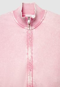 Hellrosa Zip-up-Sweatshirt mit einem gerippten hohen Kragen und einem teilweise geschlossenen, sichtbaren silbernen Reißverschluss.