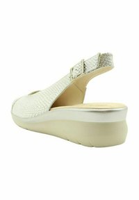 Sándala blanca de tiras tejidas con punta redondeada, correa ajustable y suela de cuña ligera para mayor comodidad y soporte.