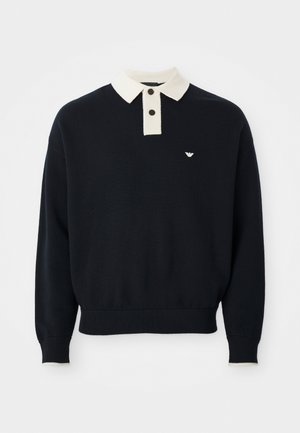Pull noir à manches longues avec un col blanc, deux boutons, des poignets et un ourlet côtelés, et un petit logo blanc sur la poitrine gauche.