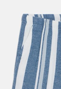 Tessuto a righe blu e bianco, caratterizzato da un motivo testurizzato. Il design include cuciture visibili e una tasca laterale. Materiale leggero.