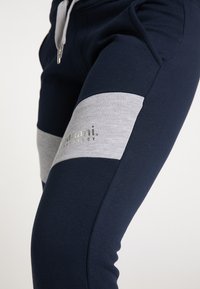 Marine joggers met grijze zijpanelen en een zilveren logo. Gemaakt van een zachte katoenmix, met een elastische tailleband en een trekkoordsluiting.