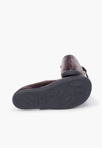 Tmavě hnědá sametová bota s kulatou špičkou, strukturovaným svrškem a gumovou podrážkou s kruhovým vzorem pro zlepšení trakce.