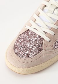 Sneaker con finitura in suede rosa, caratterizzata da un pannello glitterato in oro rosa, lacci bianchi e una suola in gomma testurizzata.