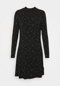 Czarna sukienka z długim rękawem i drapowanym dekoltem, zdobiona rozrzuconymi białymi kropkami w różnych rozmiarach, lekko rozszerzana w kształcie litery A.