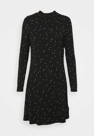 Robe noire à manches longues avec un encolure froncée, ornée de pois blancs de différentes tailles, légèrement évasée en forme de A.