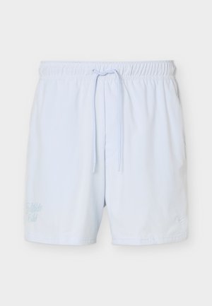 Hvite atletiske shorts med elastisk midjebånd og snor, med subtil brodert tekst på venstre ben og liten logo på høyre ben.