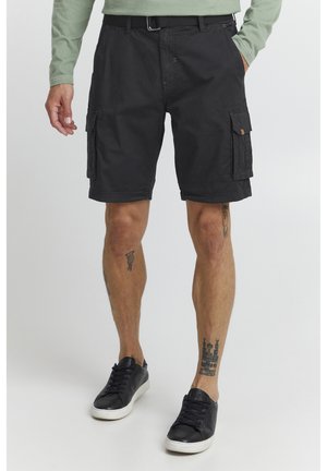 Black cargo shorts with side pockets, made of lightweight fabric. Features a belt loop and a relaxed fit. Worn with black sneakers and visible tattoos.