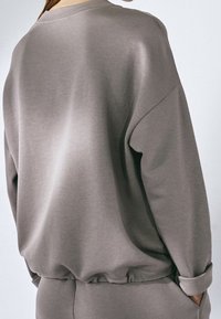 Trendy sweatshirt met lange mouwen in lichtgrijze stof. Heeft een ronde halslijn, geribbelde manchetten en zoom, met een gladde, zachte textuur.