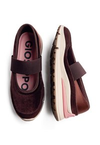 Sapatos de camurça castanhos com uma alça larga, palmilha rosa e sola de borracha de cor creme com sola exterior castanha texturizada para tração.