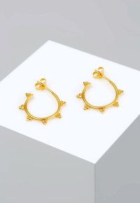 Goldene Creolen mit einem runden Design, die kleine dekorative Akzente entlang der Kante aufweisen und einen sicheren Stecker-Verschluss haben.