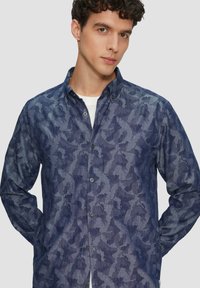 Marineblauw overhemd met knopen, vervaardigd uit een textuurstof met een subtiel abstract patroon, lange mouwen en een klassiek kraagontwerp.