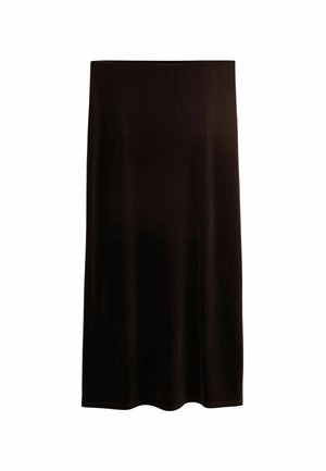 Femme portant un pull manches courtes bleu marine, une jupe en velours marron foncé, des bottes en cuir marron pointues et tenant un sac à bandoulière grenat.