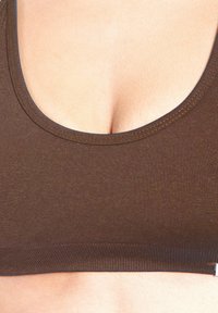 Top corto de tela marrón y elástica con escote redondeado. Presenta una textura lisa y costuras reforzadas a lo largo de los bordes.
