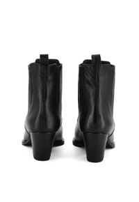Stivaletti neri in pelle con punta arrotondata, pannelli laterali testurizzati e tacco di altezza media. Presentano delle linguette per una vestibilità facile.