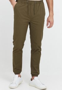 Olivegröna joggers i lättviktsmaterial, med elastisk midja och dragsko, sidofickor och elastiska muddar.