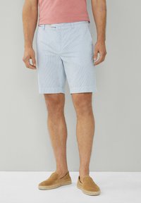 Ljust blå randiga shorts i ett tyg med en slät yta, med vikta fållar och sidofickor. Bärs med bruna slip-on skor.