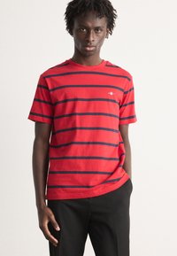 Rød og marineblå stribet kortærmet T-shirt lavet af bomuld, med rund hals og et lille logo på venstre bryst.