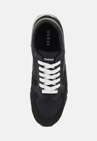 Sneaker nero con lacci bianchi. Presenta un tessuto testurizzato, logo sulla linguetta e suola in gomma con una striscia a contrasto. Design con punta tonda.