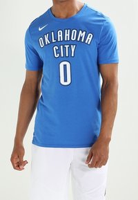 Niebieska bawełniana koszulka z napisem "OKLAHOMA CITY" w białych i czarnych literach, z numerem "0" poniżej. Logo Nike w górnym lewym rogu.