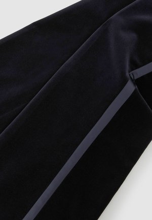 Zbliżenie czarnej aksamitnej tkaniny z gładką wstążką przypominającą satynę, biegnącą po skosie wzdłuż materiału.