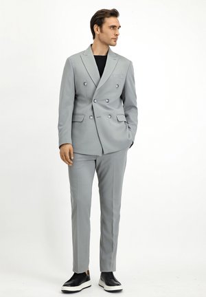 Conjunto gris de traje de doble botonadura que presenta una tela texturada, corte ajustado y solapas de muesca, combinado con elegantes zapatos negros tipo mocasín.
