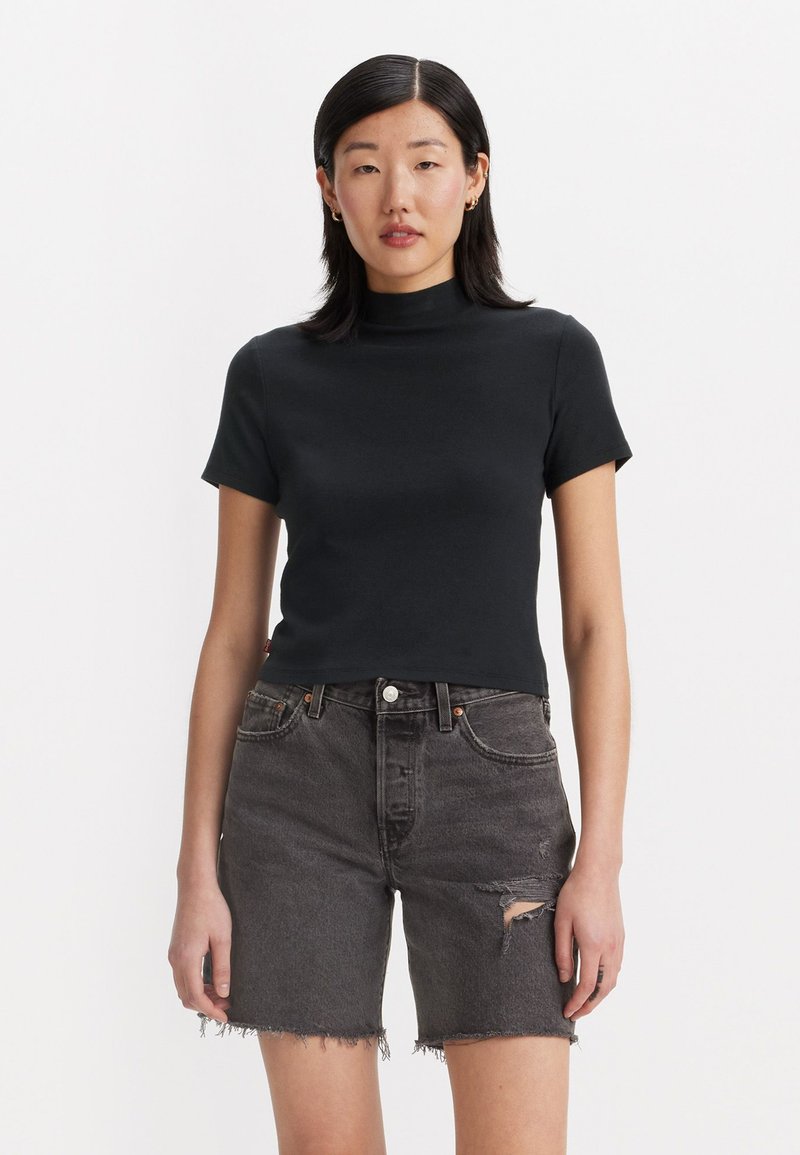 Haut noir à col montant à manches courtes, ajusté, associé à un short en denim gris taille haute avec un effet usé et des ourlets effilochés.