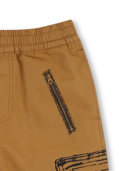 Pantaloni di cotone marrone con una zip nera laterale, cuciture visibili e superficie texturizzata.