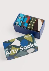Četiri para smotanih čarapa u plavoj kutiji. Uzorci uključuju dijamante, pruge i geometerske oblike. Kutija ima šareni geometrijski dizajn.