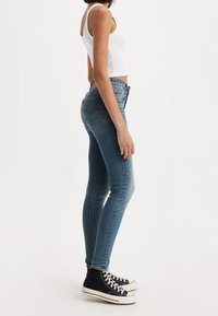 Smala blå jeans i denim, med medelhög midja, subtilt blekning och en klassisk femfickorsdesign. Kommer med svarta högkängor.