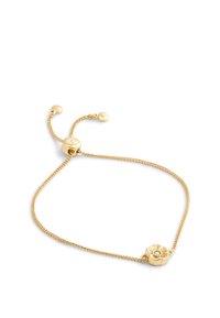 Bracciale d'oro con un design a catena, caratterizzato da un ciondolo a forma di fiore con un accento centrale in pietra. Chiusura regolabile con estremità arrotondate.