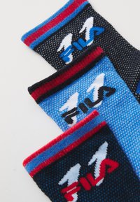 Tre paia di calze lavorate a maglia in nero, blu e blu scuro con strisce rosse e blu, dotate di un logo FILA stilizzato vicino al polsino.