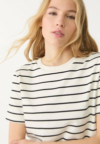 Gestreepte t-shirt met zwarte horizontale strepen op een witte achtergrond, ronde halslijn en korte mouwen, gemaakt van zacht katoen.
